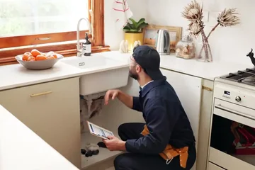 Plumber working under a kitchen sink